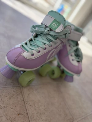 Pastellfärgade rullskridskor från Rio - Snygga rullskridskor i pastellila, mintgrönt och vitt från Rio Roller. Klassisk retrodesign med högt skaft, snörning och kardborreband. Hjul och tåstopp i matchande färger. Perfekta för dig som vill sticka ut på rinken eller gatan.