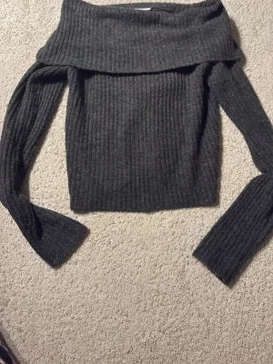 Mörkgrå off shoulder stickad tröja - Använd en gång då jag fick den i present och jag ej gillade så mycket. Jätteskönt material och jättefint med off shoulder! Storlek 158/164 men skulle säga att den passar xs/s! Mysig mörkgrå stickad tröja från Kappahl med off shoulder-design och bred krage. Tröjan har ribbstickat mönster och långa ärmar, perfekt för kyliga dagar. Enkel att matcha med jeans eller kjol. Inga slitningar!