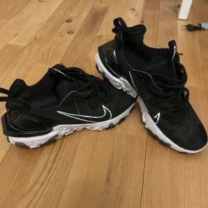 Nike React V2. Svart/vit - Snygga svarta Nike sneakers. Perfekta för både träning och vardag. De finns skador på skor och säljer då för  jag vill bli av med dem. Pris går att diskuteras vid snabb affär 