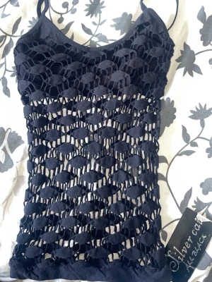 Svart nätmönstrad linnetopp Silvercat - Cool svart linnetopp från Silvercat med unikt nätmönster och smala axelband. Toppen är ärmlös och har en croppad passform som ger en edgy vibe. Perfekt att styla över ett linne eller bikini för en trendig look.