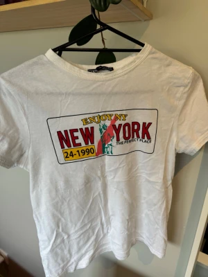 Vit t-shirt med New York-tryck - Snygg vit t-shirt med färgglatt New York-tryck framtill och motiv av Frihetsgudinnan.
