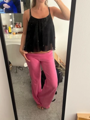Svart lös topp med tunna band - Säljer en svart, luftig topp med tunna axelband. Toppen har ett flowy fall och är lätt transparent, perfekt för en trendig och avslappnad look. Passar snyggt till både jeans och kjol.