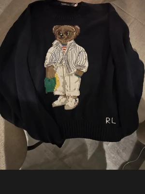 Mörkblå stickad tröja med björnmotiv Ralph lauren hoodi - Säljer en mörkblå stickad tröja från Ralph Lauren med ett björn i mitten passar alla typer av stillar 