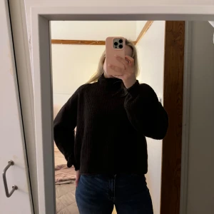 Mörkbrun stickad polotröja - Säljer en mörkbrun stickad polotröja med avslappnad passform och ribbade muddar. Tröjan har hög krage och långa ärmar, perfekt för kyligare dagar. Passar till jeans eller kjol för en enkel och snygg look. Tröjan är från Vera Moda i storlek S