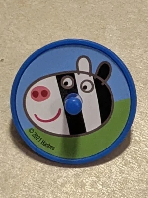 Snurra från Hasbro - Rolig snurra i plast med blå kant och ett färgglatt motiv på framsidan. Baksidan är helblå med små hål och ett greppvänligt handtag. Perfekt för dig som gillar snurrleksaker och djurmotiv.