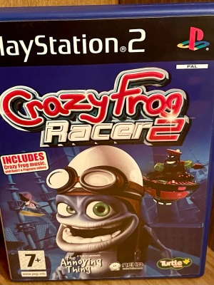Crazy Frog Racer 2 till PS2 - Crazy Frog Racer 2 är ett racingspel till PlayStation 2 där du tävlar som Crazy Frog och andra karaktärer i färgglada banor. Spelet har blå plastfodral och innehåller musik och videor med Crazy Frog. Perfekt för dig som gillar fartfyllda och galna race med humor.