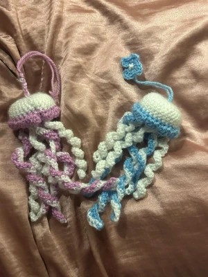 Virkade maneter, kan göra custom - Handgjorda virkade maneter i vitt, blått och rosa garn, eller i valfri färg av dig. De har en ögla för att hänga upp eller ha på nyckelringen, den blå har även en liten virkad blomma som ett exempel på sånt man kan lägga till. Perfekt som dekoration eller present.