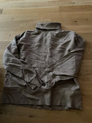 Beige polotröja från 157 - Säljer en beige stickad polotröja från 157 i storlek M. Tröjan har ribbade muddar och hög krage, perfekt för lager på lager. Materialet är mjukt och stretchigt, vilket gör den skön att bära hela dagen.