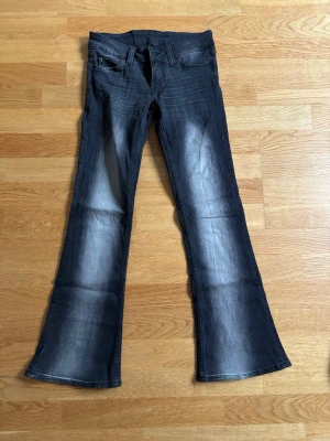 Svarta bootcut jeans från Cheap Monday - Säljer ett par svarta bootcut jeans från Cheap Monday med ljusare partier framtill och baktill. Jeansen har klassisk femficksmodell och en lila logga bak i midjan. Materialet är denim med lite stretch för skön passform. Säljer pga ingen användning😚
