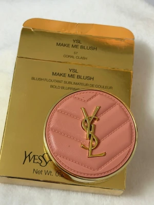 YSL Make Me Blush Coral Clash - Lyxigt rouge från Yves Saint Laurent i nyansen Coral Clash. Kommer i en rund, guldig dosa med quiltad rosa ovansida och YSL-logga i guld. Pudret har en mjuk korallfärg och är pressat med YSL-mönster. Perfekt för en fräsch och glowig look.