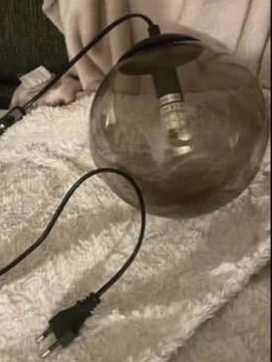Rund fönsterlampa i rökfärgat glas - Säljer en modern lampa med rund kupa i rökfärgat glas och svart sladd. Lampan har en synlig glödlampa och passar perfekt som inredningsdetalj. Strömkontakt för vanligt eluttag.