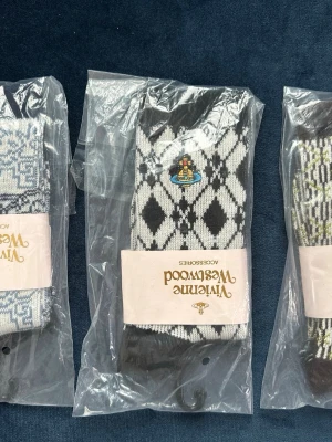 Vivienne Westhood strumpor 3par  - Säljer ett par svarta och vita strumpor med klassiskt rutig mönster och en liten broderad detalj framtill. Strumporna är från Vivienne Westwood och är tillverkade i mjuk bomullsmix. Perfekta för dig som vill ha något extra till outfiten.
