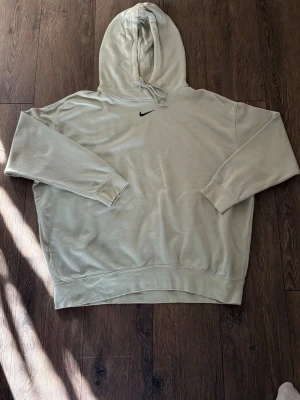 Mint vintage hoodie från Nike med huva - Snygg mint vintage hoodie från Nike med klassisk huva och dragsko. Diskret svart Nike-logga broderad på bröstet. Hoodien har ribbade muddar vid ärmslut och nederkant, samt en avslappnad passform. Perfekt för en chill och sportig look.