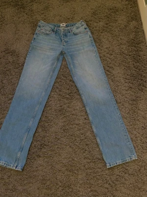 Lågmidjade Ljusblå raka jeans från 157 - Säljer ett par lågmidjade ljusblå jeans från 157 med klassisk femficksdesign och raka ben. Jeansen har en snygg tvättad look och är tillverkade i bomull. Perfekta för dig som gillar en enkel och stilren jeansstil.