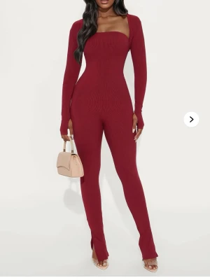 Vinröd ribbad jumpsuit med långa ärmar - Snygg vinröd jumpsuit i ribbat stretchmaterial med figurnära passform och långa ärmar. 