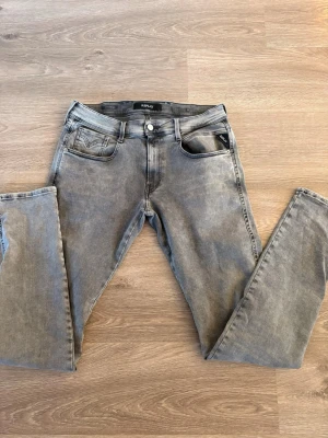 Gråa Replay jeans med raka ben - Säljer ett par gråa jeans från Replay med raka ben och klassisk femficksmodell. Jeansen har en snygg tvättad look och detaljerade bakfickor med broderi. Tillverkade i bomull med en skön passform. Perfekta för en avslappnad stil.