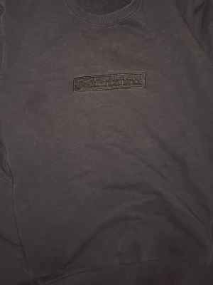 Svart sweatshirt Peak Performance - Snygg svart sweatshirt från Peak Performance med diskret broderad logga på bröstet. Klassisk rund halsringning och ribbade muddar vid ärmslut och nederkant. Perfekt till ett avslappnat streetwear-look.