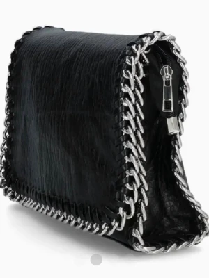 Svart handväska med kedjedetaljer - Vita fläckar på insidan men inget som syns vid användning, tror det är smink. Snygg svart handväska, perfekt accessoar för en trendig look.