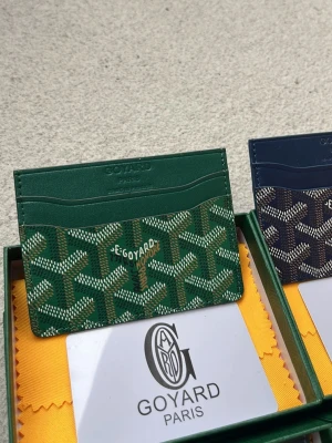 Grön plånbok från Goy4ard - Snyggt grönt kortfodral från Goy4ard med det klassiska mönstret och loggan tryckt på framsidan. Fodralet har flera fack för kort och är gjort i exklusivt läder med canvasdetaljer. Perfekt för dig som vill ha något stilrent och lyxigt i fickan.