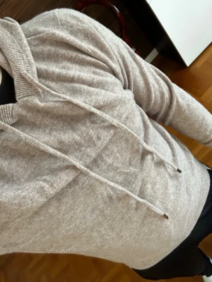 Mörk beige merinoull hoodie  - Mysig mörkbeige merinoull hoodie. Perfekt för en avslappnad look och enkel att matcha med andra plagg.