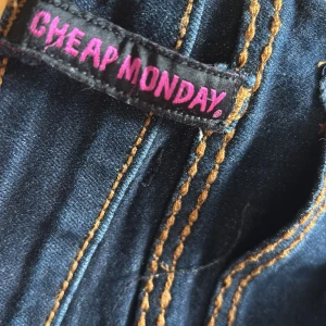 Bootcut jeans från Cheap Monday, mörkblå - Mörkblå bootcut jeans från Cheap Monday med kontrastsömmar. Snygg passform med utsvängda ben och låg midja. Perfekta för dig som gillar retrovibbar.