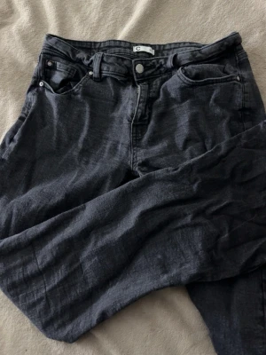 Svarta bootcut jenas från Cubus - Säljer ett par svarta jeans från Cubus med bootcut passform och klassisk femficksdesign. Jeansen har låg midja, knappgylf och är tillverkade i ett mjukt denimtyg. Perfekta för en avslappnad och stilren look.
