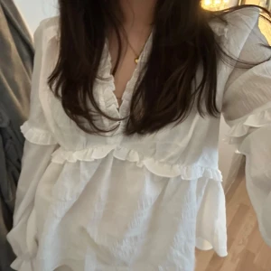 Vit volangblus med v-ringning - Söt vit blus med v-ringning och volangdetaljer. Aldrig andvänd. Köpt från nakd 💕