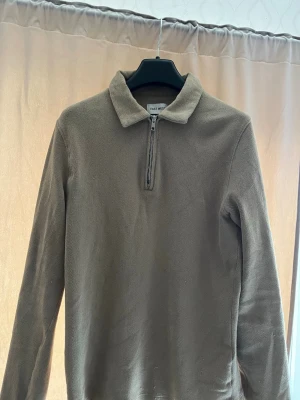 Beige ziptröja från EAST WEST - Säljer en beige långärmad ziptröja från EAST WEST. Tröjan har en klassisk krage och dragkedja framtill. Perfekt för dig som gillar stilrena och enkla plagg nu till sommaren!!