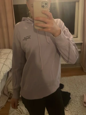 Ljuslila hoodie från Better With Kraft - Säljer en ljuslila hoodie från Better With Kraft. Hoodien har huva med dragsnören och tryckt logga på bröstet. Mjuk och skön passform, perfekt till chill dagar. Långa ärmar och ribbade muddar vid ärmslut och nederkant.