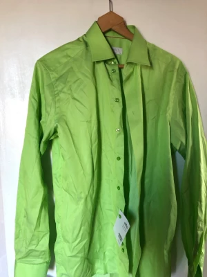 Grön skjorta från Eton, långärmad - Snygg grön skjorta från Eton i modellen Contemporary. Skjortan har klassisk krage, långa ärmar och knappar framtill. Tillverkad i bomull och passar perfekt för dig som vill sticka ut med färg.