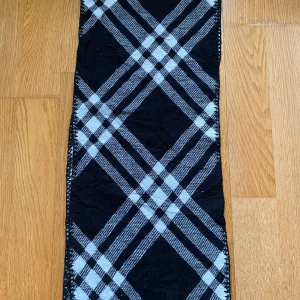Rutig svartvit halsduk från Burberrys - Klassisk halsduk från Burberrys i svart och vitt med rutigt mönster. Tillverkad i 100% lammull vilket gör den både mjuk och varm. Perfekt accessoar för att lyfta din outfit med en tidlös look.