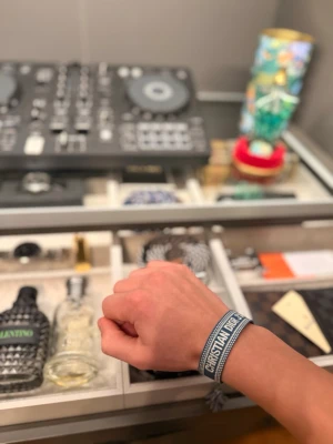 Christian Dior armband - Snyggt blått armband från Christian Dior med vit brodyr och texten 'Christian Dior' på framsidan. Armbandet har justerbar knytning med tofsar i ändarna och är gjort i textilmaterial. Perfekt accessoar för att lyfta din outfit.