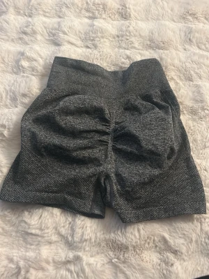 Grå träningstights shorts - Grå, högmidjade träningstights shorts med tight passform och scrunch-detalj bak. Perfekta för gymmet eller andra träningspass. Mjukt och stretchigt material för maximal komfort. Använd 2 gånger