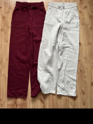 Två par mjukisbyxor, vinröd & grå - Säljer två par mjukisbyxor, ett par i vinrött och ett par i ljusgrått. Båda har resår i midjan, dragsko och stora fickor fram och bak. Perfekta för chill dagar eller när du vill vara extra bekväm. Mjukt material, troligen bomullsblandning. Lite noppiga annars inget fel på dem