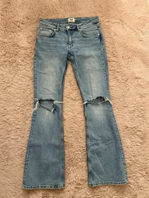 Ljusblå bootcut jeans med slitningar - Säljer ett par ljusblå bootcut jeans från 157 med slitna knän i storlek S. Jeansen är använda men finns inga tecken på användning🥰🥰💕😇