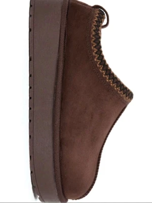 Bruna mockatofflor med platåsula från Lager157  - Säljer ett par bruna tofflor i mocka med hög platåsula och dekorativt stickat mönster runt öppningen. Tofflorna har en chunky look och är perfekta för att hålla fötterna varma inomhus. Snygg och trendig design som passar till myskvällar.