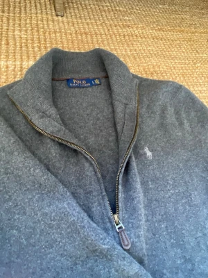 Grå ziptröja från Polo Ralph Lauren 100% merinoull - Mysig grå ziptröja från Polo Ralph Lauren med hög krage och dragkedja. Tröjan har det klassiska broderade logot på bröstet och är tillverkad i mjukt material som känns lyxigt. Perfekt för lager på lager och chill stil. Det står large men skulle säga att den är  S/M.
