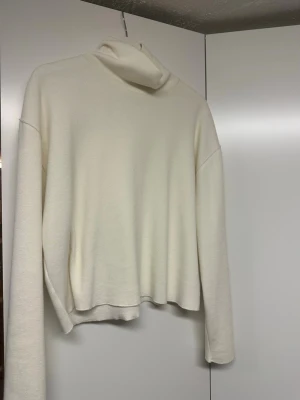 Vit polotröja från Zara - Klassisk vit stickad polotröja från Zara med lång ärm och avslappnad passform. Tröjan har hög polokrage och är tillverkad i mjukt material som passar perfekt för kyligare dagar. Enkel och stilren design som är lätt att matcha. Liten i storleken så skulle säga att den sitter som en M/S