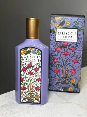 Gucci Flora Gorgeous Magnolia parfym - Gucci Flora Gorgeous Magnolia är en parfym i en lila, rektangulär flaska med guldfärgat lock. Flaskan har en färgglad blommig etikett och kommer i en matchande ask med blommönster. Doften är inspirerad av magnolia och har en elegant, lyxig känsla.