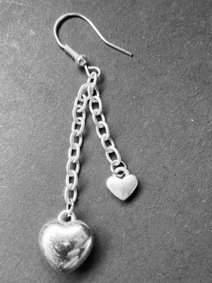 By prisförslag- 1 st Silverfärgat örhänge med hjärtan - Snyggt örhänge i silverfärg med två kedjor och hjärtformade hängen. Ett större och ett mindre hjärta ger en cool och lekfull look. Passar perfekt för dig som gillar detaljer och vill sticka ut lite extra. Materialet är metall och designen är modern med en touch av romantik.