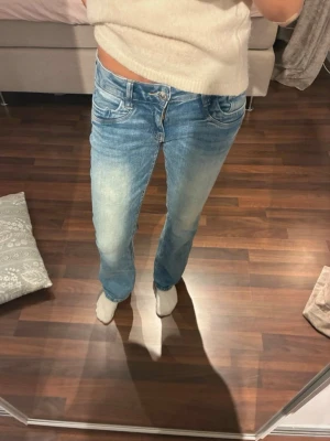 Blå raka jeans från Gina Tricot - Säljer ett par ljusblå utsvängda lågmidjade jeans från Gina Tricot med klassisk fickor. Jeansen är tillverkade i denim med en skön känsla. Perfekta till en avslappnad vardagsstil.