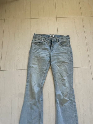 Ljusblå bootcut jeans från lager 157 - Säljer ett par ljusblå jeans från lager 157 med klassisk femficksmodell och bootcut-ben. Jeansen har bälteshällor, knappgylf och är tillverkade i mjuk denim. Perfekta för en avslappnad och trendig look.