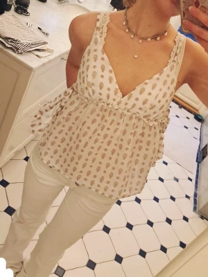 vit omlottop med knyten och mönster - supersöt vit linnetopp med beiga/bruna mönster och knyten på sidorna💕 säljer pga att jag nästan aldrig använt!! toppen är i storlek 34 vilket motsvarar S/XS