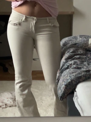 Vita low waist bootcut jeans - Säljer ett par vita bootcut jeans med klassiska fem fickor och normalhög midja. Jeansen har en snygg passform som sitter tajt över låren och släpper ut vid bensluten. Perfekta till en avslappnad eller trendig look.
