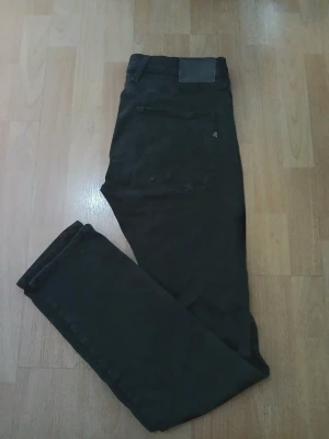 Svarta Replay Anbass jeans slim fit - Säljer ett par svarta Replay Anbass jeans i herrmodell. De har en slim passform med klassisk femficksdesign och snygga detaljer på bakfickan. Jeansen är tillverkade i stretchigt bomullsmaterial för extra komfort och har en stilren look som funkar till många outfits. W34, L34. Nypris: 849kr / Mitt pris: 349kr