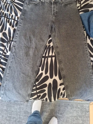 Grå loose fit jeans från Loose/Eddie - Säljer ett par grå loose fit jeans från Loose/Eddie. Jeansen har en avslappnad passform med raka ben och klassisk femficksdesign. Materialet är kraftigt denim i tvättad grå nyans, perfekt för en chill och trendig look.