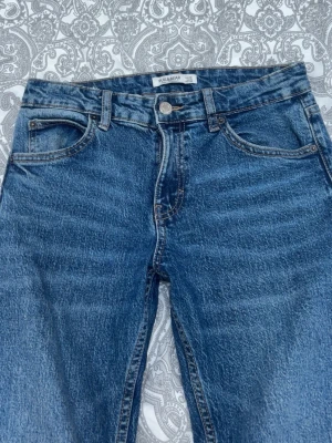 Blå raka jeans från Pull&Bear - Snygga straight jeans från Pull&Bear, jeansen har lite slitningar längst ner. Vet inte om det ska se ut så eller om det var så från början, bra skick annars. Säljer eftersom att dom är för små i midjan på mig.