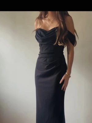 Svart off-shoulder balklänning  - Svart långklänning med offshoulder-design och draperad urringning från Bubbleroom. Oanvänd och köpt för 880kr. Aldrig använd då jag valde en annan balklänning. Jag är 165 cm lång och den är perfekt i längden, speciellt med klack. Klänningen har en figurnära passform och är tillverkad i ett mjukt, följsamt material och en inbyggd gömd ”korsett” liknande del på magen. Skriv för fler bilder 🩷Pris går att diskutera vid snabb affär 