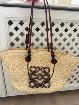Strandväska   - Snygg shoppingväska i flätad strådesign   med bruna handtag. Perfekt storlek för att få plats med allt du behöver. Väskan har en avslappnad men ändå lyxig känsla och passar till många olika outfits. Köpt utomlands. Skriv för mer info. Priset kan diskuteras vid snabbaffär. Använt ett fåtal gånger 