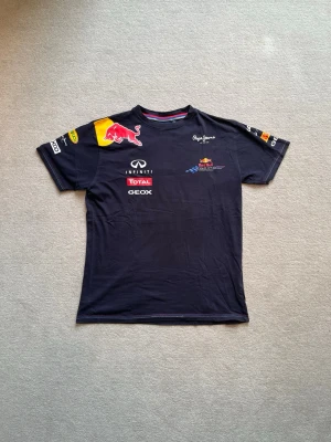 Red Bull Racing t-shirt - Tjena, säljer en mörkblå Red Bull Racing x Pepe jeans t-shirt med tryck på både fram- och baksida. Skicket är bra, skulle säga 8,5/10. Stoleken är S. Släng iväg ett dm för frågor! 🙌🍾